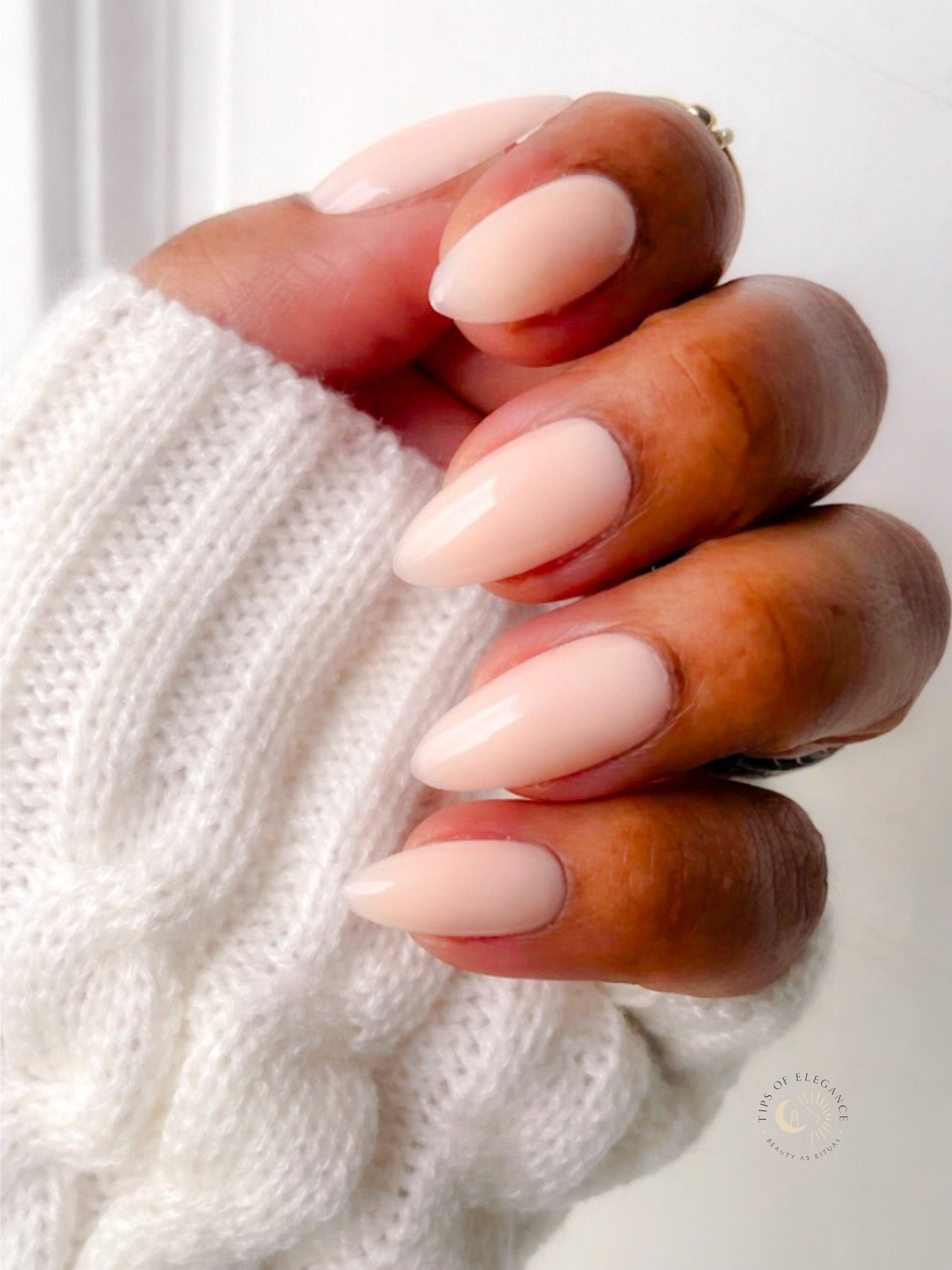 Hand with almond-shaped nails wearing a white sweater