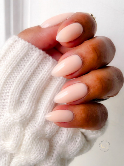 Hand with almond-shaped nails wearing a white sweater
