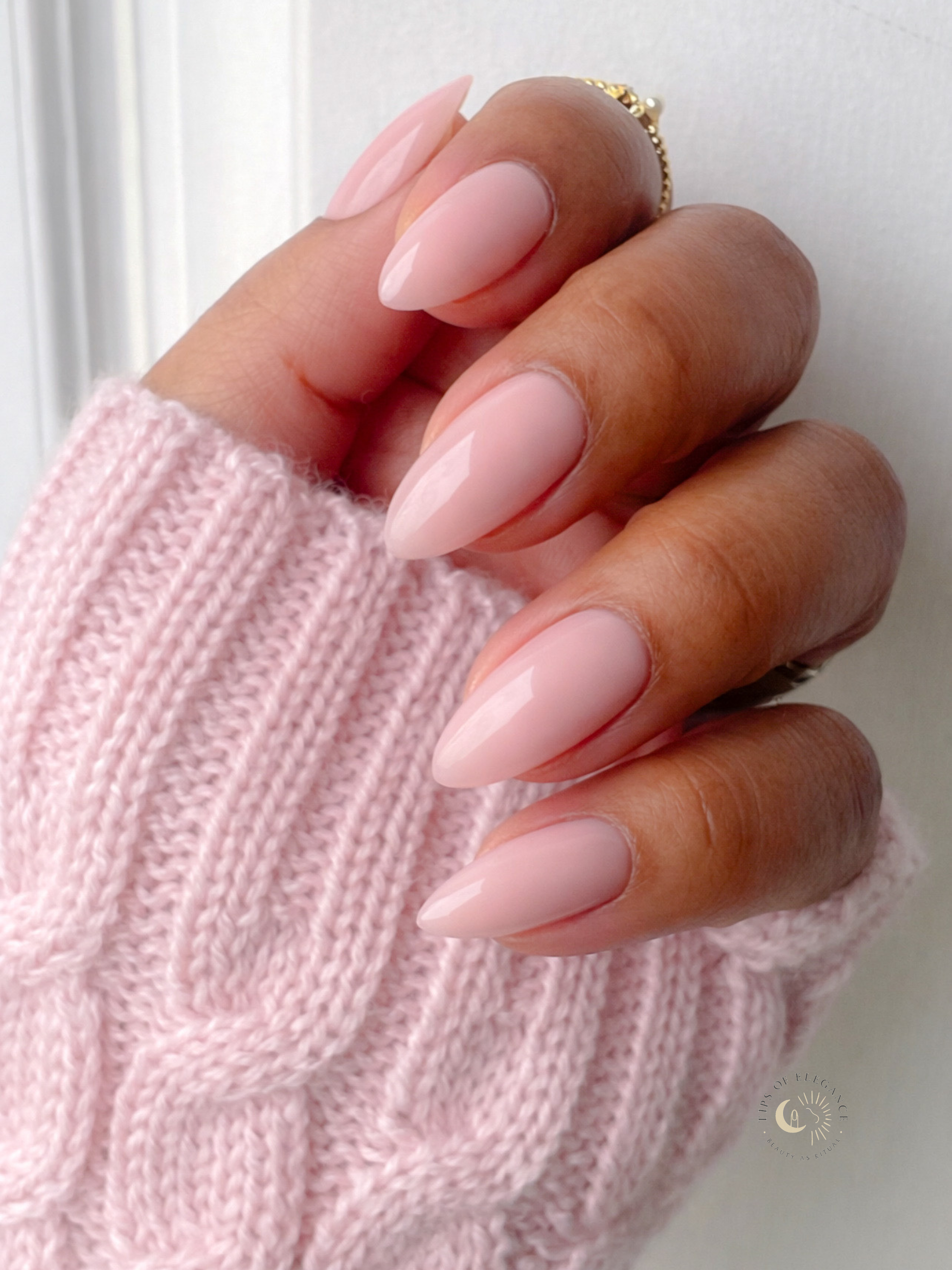 Hand with pink nail polish wearing a pink sweater